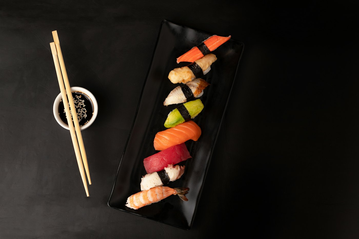 Nigiri sushi and chopsticks on a dark slate